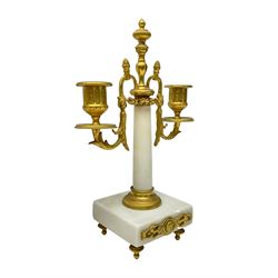 French - Late 19th century 8-day white marble and gilt metal portico clock garniture, the clock surmounted by an urn and raised on a pair of cylindrical pillars above a rectangular plinth base, white enamel dial with Arabic numerals and floral garlands, twin train countwheel striking movement, striking the hours and half hours on a bell, with a sunburst pendulum and gilt Louis XVI hands, garniture with matching twin light candelabra. With Key.   Candelabra H 30cm.