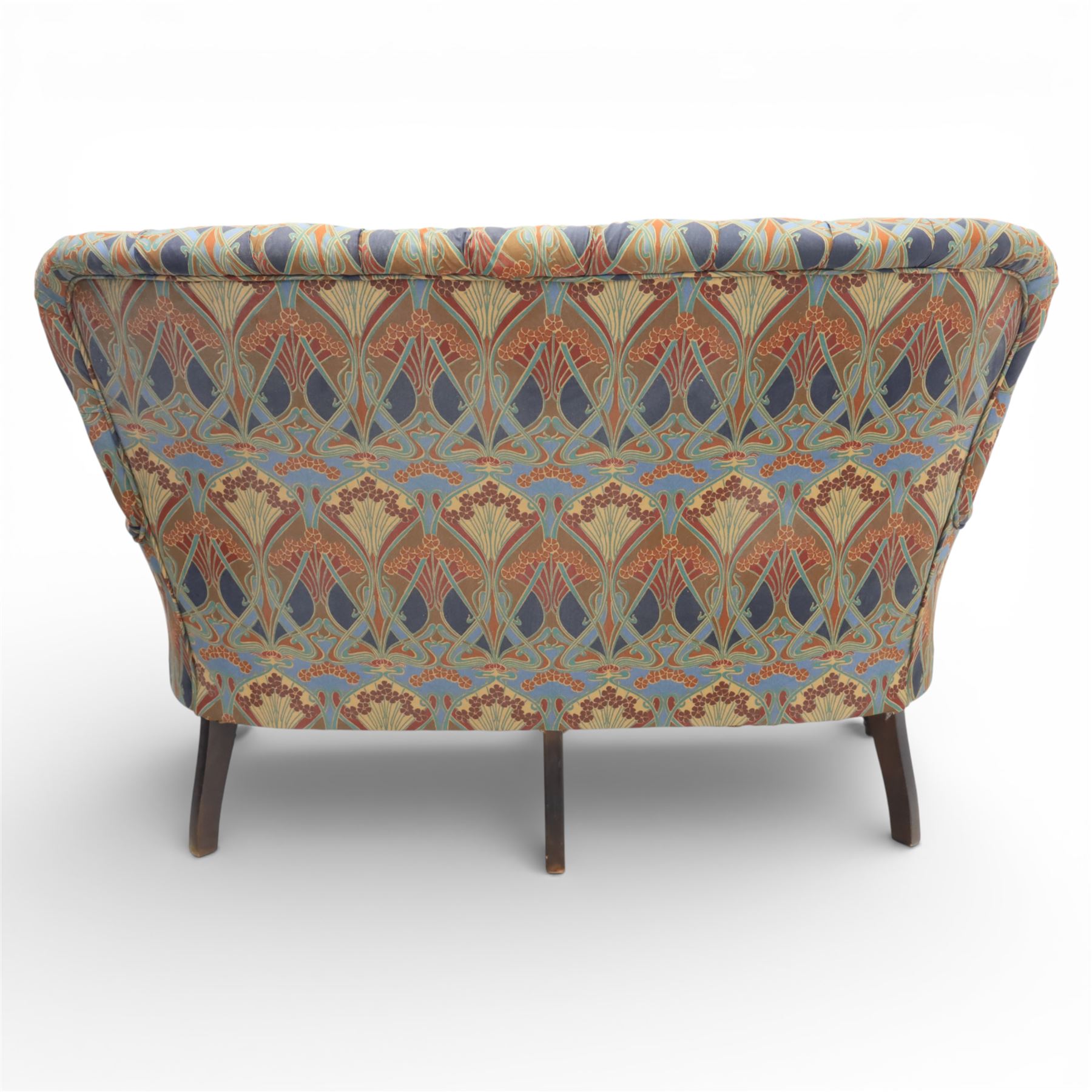 Late 20th century Liberty upholstered two seater sofa, the shaped back and arms with deep buttoned upholstery, covered in Art Nouveau fabric with stylised floral and foliate motifs, loose scatter cushions en suite, raised upon turned tapering front supports and swept rear legs