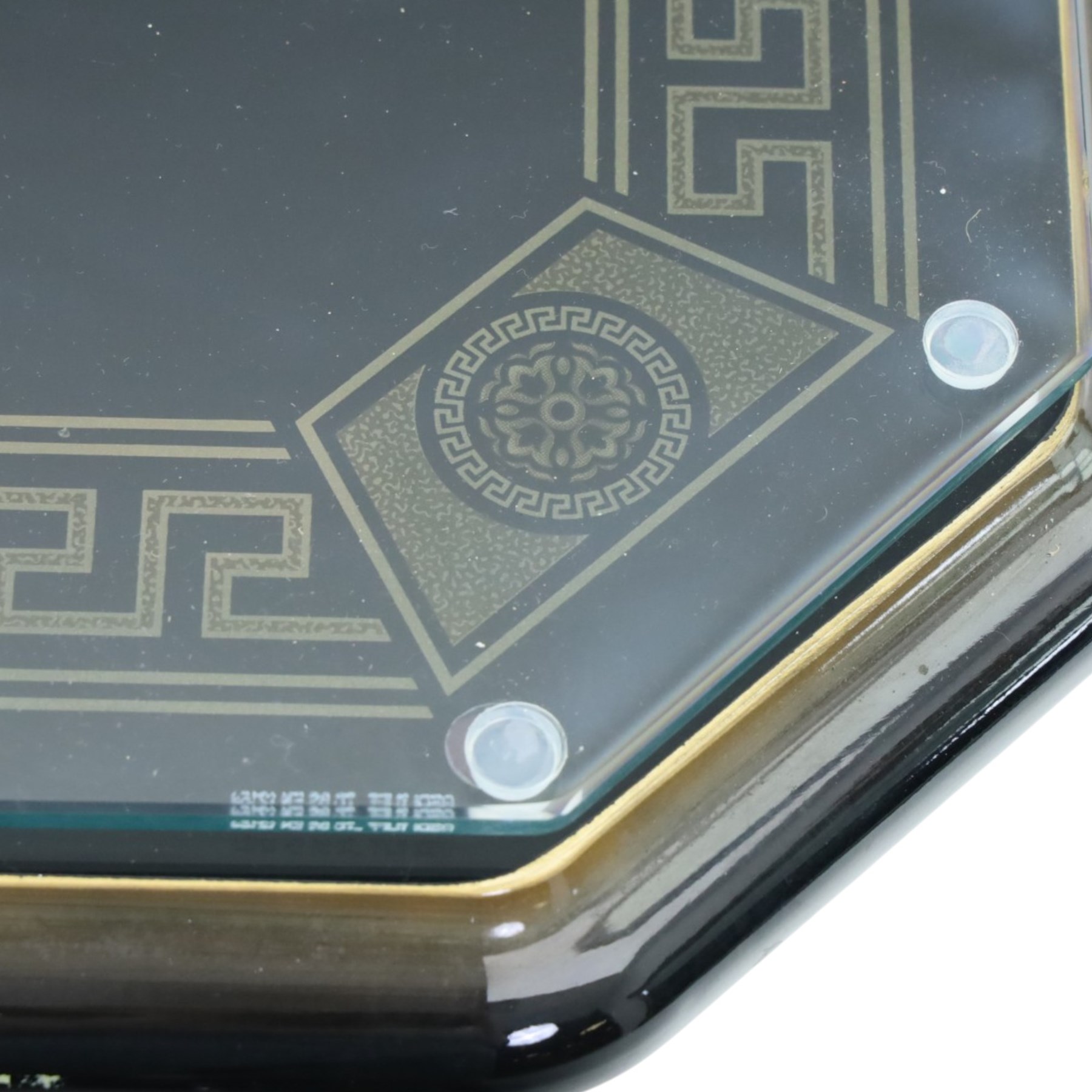 Italian Neoclassical inspired ebonised gloss coffee table, glazed cantered top with Greek key banding, on a shaped pedestal base with gilt highlights and stepped plinth 
