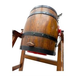 19th century oak and cast iron rotary butter churn, with coopered barrel body, domed lid with filler opening and cast iron securing arms, on tilting iron-mounted frame with crank handle and support rails