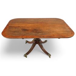 Early 19th century Sheraton style mahogany and rosewood pedestal breakfast table, the rectangular top with rounded corners and crossbanded edge, raised on a turned column support with reeded detail, terminating in four splayed legs with brass caps and castors