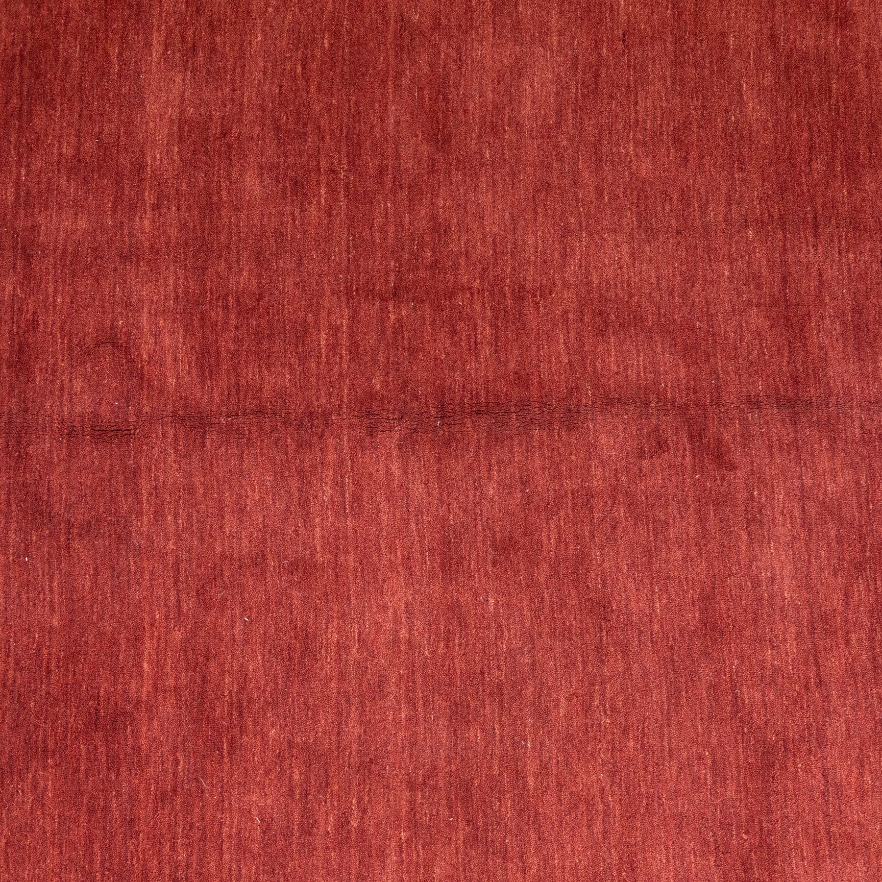 Modern Gabbeh red wool rug, plain madder red field with subtle tonal variation and abrash