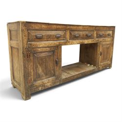 18th century rustic oak dresser base, with fielded panels and iron cup handles with embossed greek key and foliate detail, three short drawers above and open recess flanked by two cupboard doors, raised on stile supports
