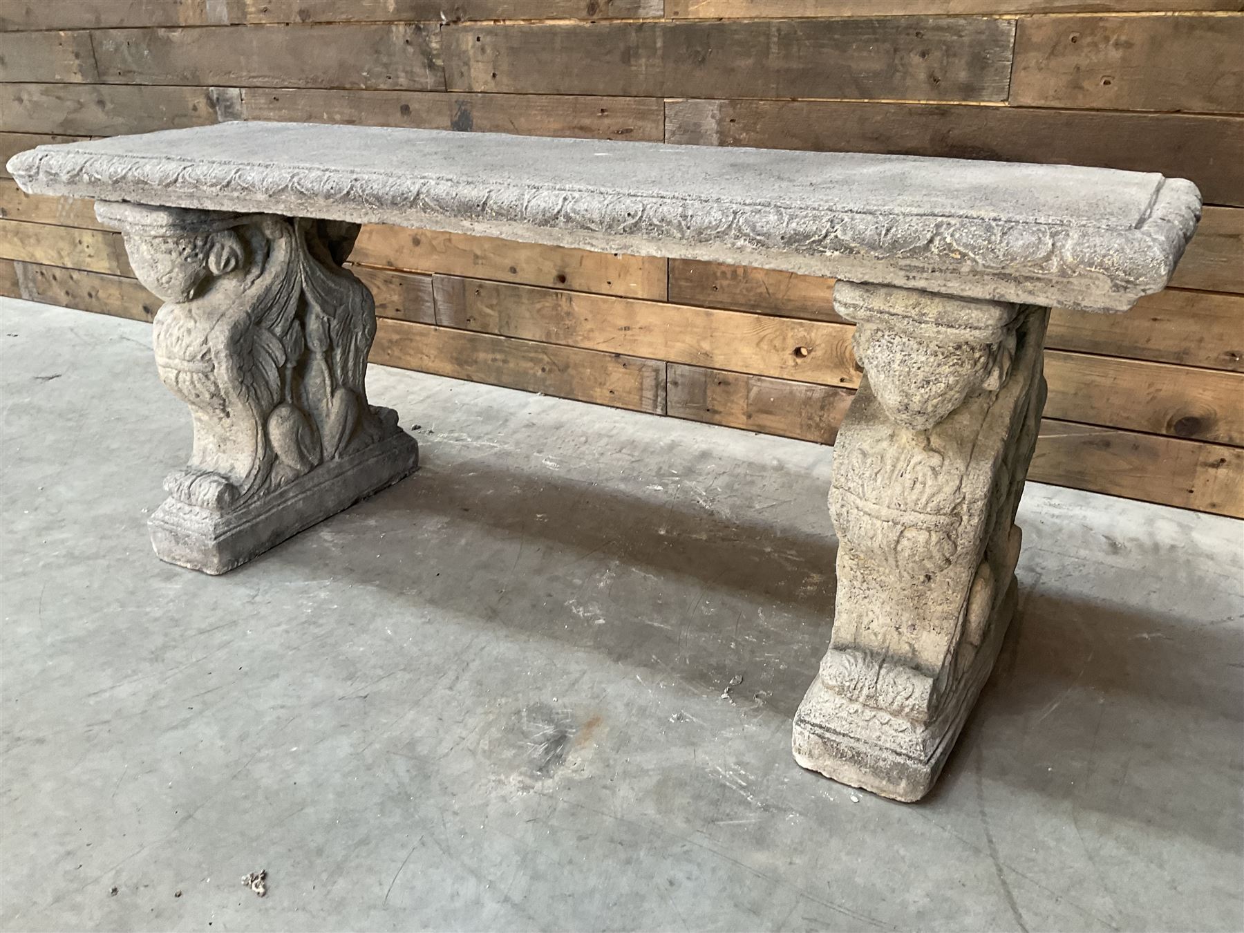 Cast stone garden Rams Head bench, two pillars set with architectural rams heads, rectangular slab seat