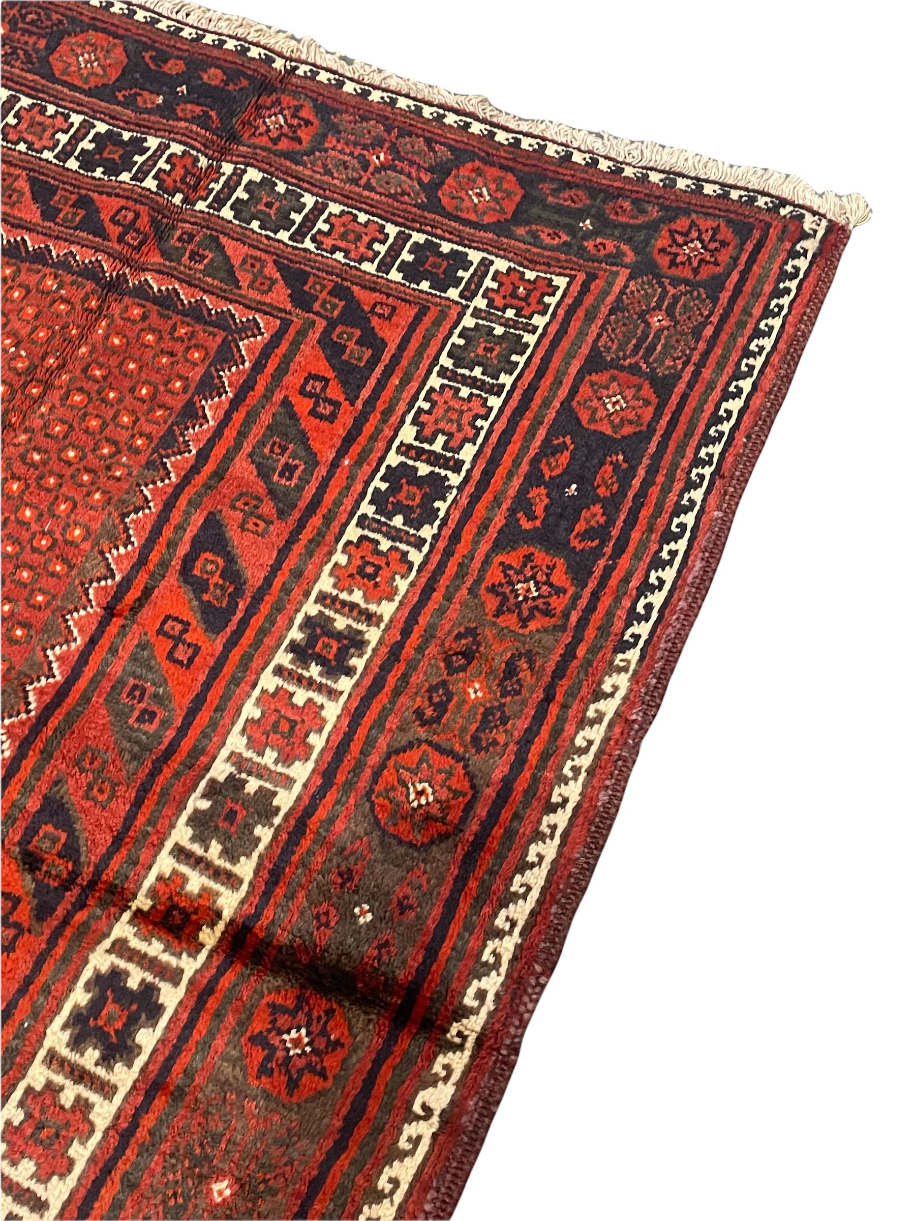 Persian Kelardasht red ground rug, the field decorated with two geometric medallions, multi-band border decorated with stylised flower heads and geometric repeating patterns