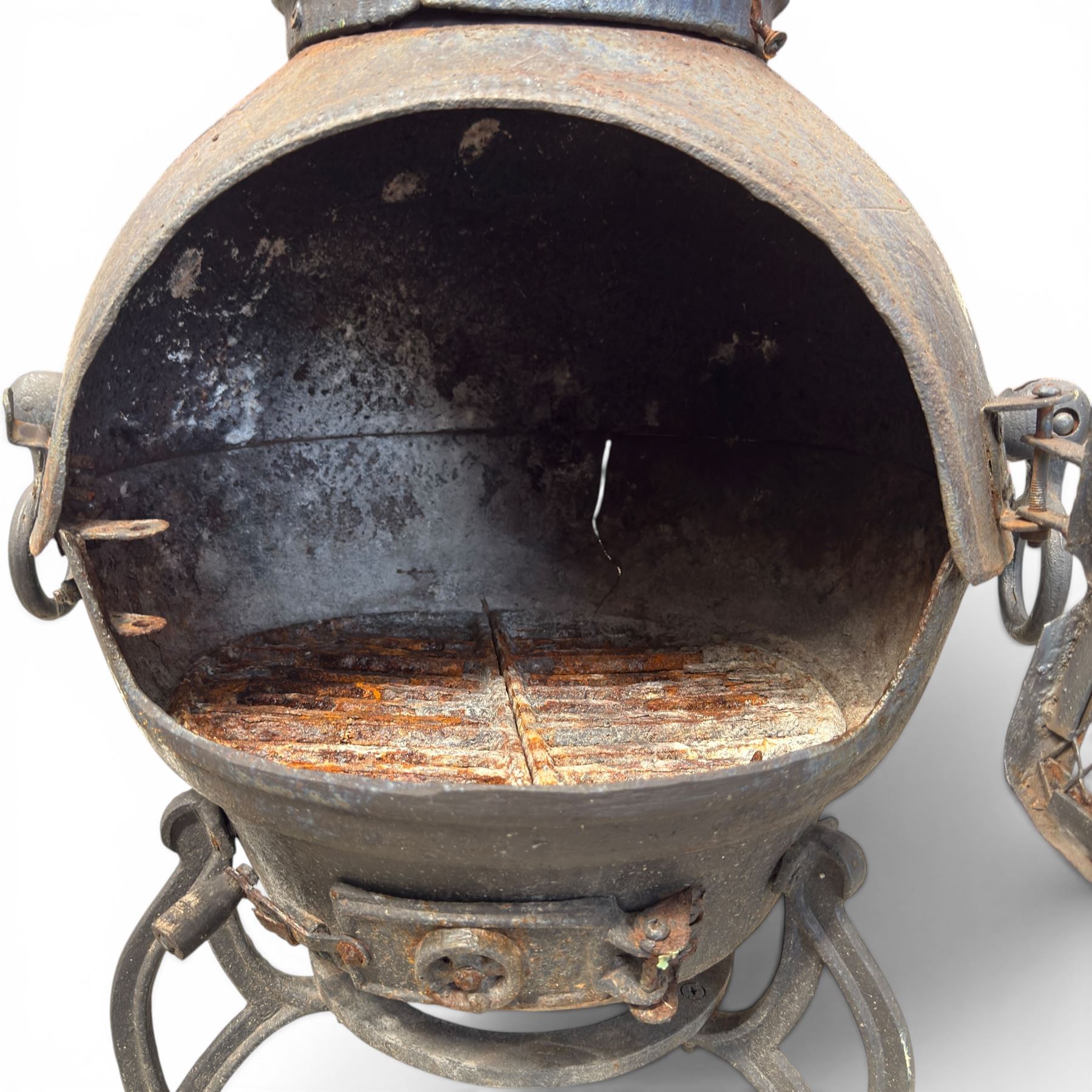 Cast iron garden chiminea, with mesh front spark guard, flue chimney on three splayed legs, finished in black.