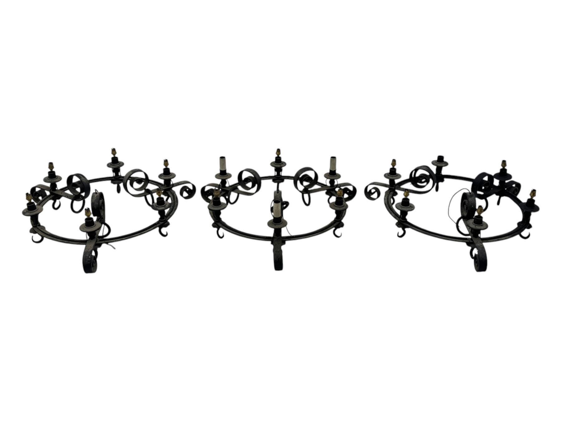 Set of three mid-20th century wrought iron six-light chandeliers, each with a circular frame with scrolled arms, faux candle sleeves and hook terminals