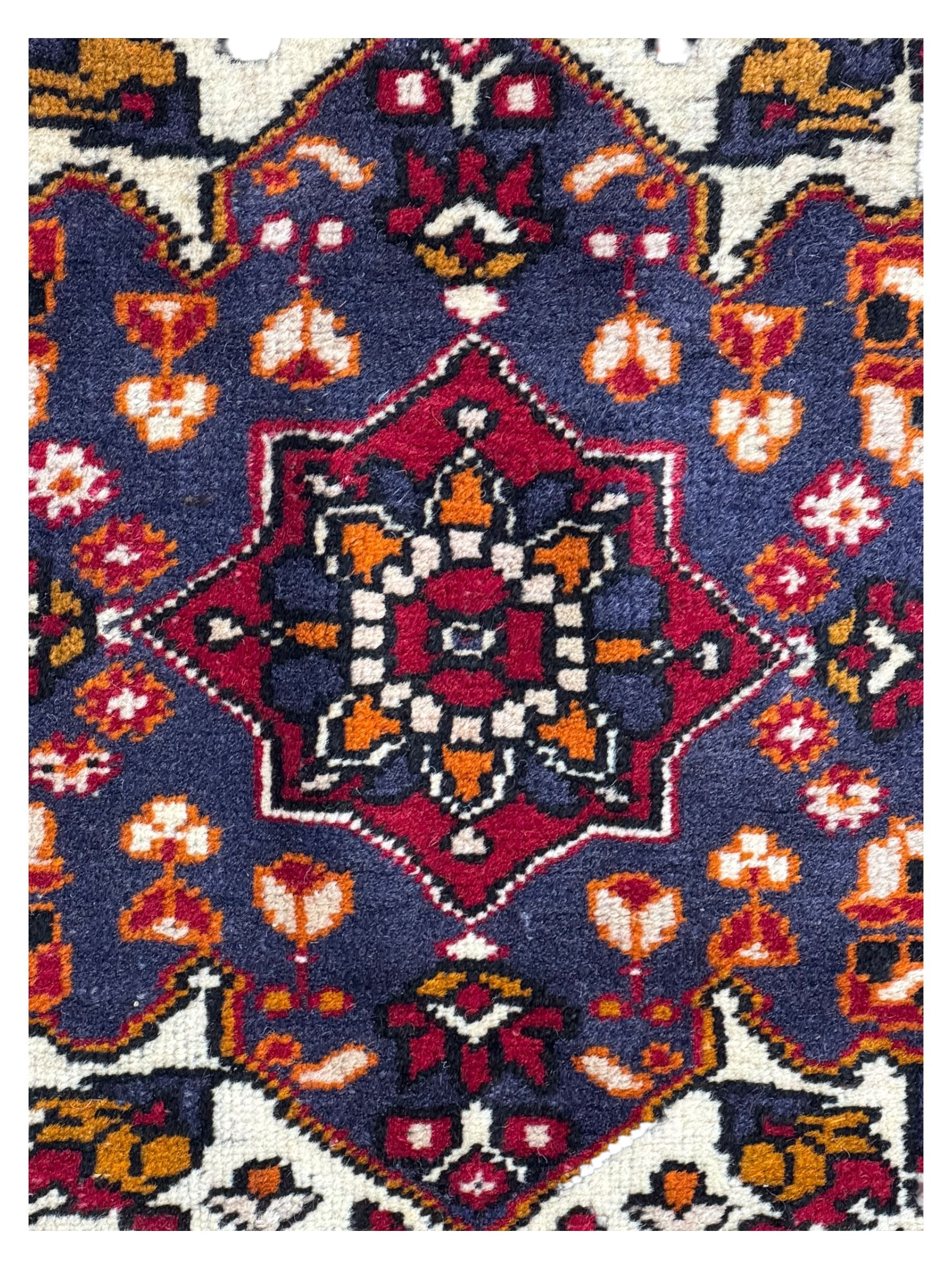 West Persian Hamadan rug, hand knotted, central medallion bordered by geometric and intricate floral motifs, displaying red cream and indigo colours with an orange coloured border  