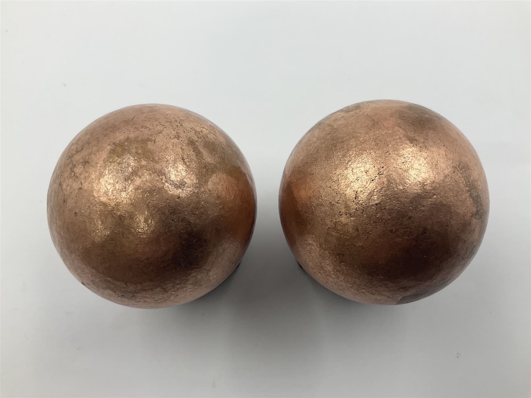 Pair of copper spheres, upon carved wooden bases, D5cm 