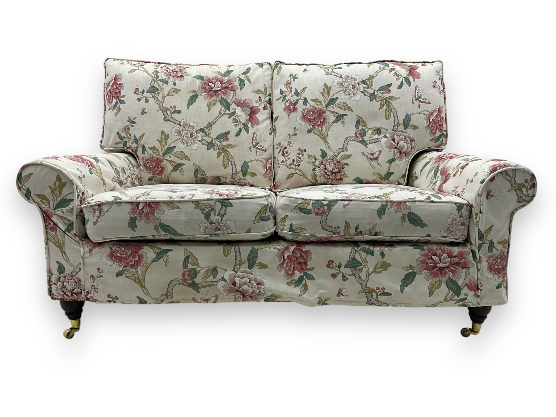 Steed Upholstery - 'Knightsbridge' two seater sofa, upholstered in cream fabric with pink and green floral design, loose back and seat cushions, raised on mahogany supports with brass castors
