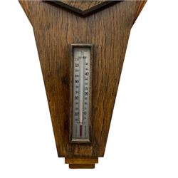 A mid-20th century British made aneroid barometer housed in an inverted oak case in the art deco style,  with a six-inch silver effect dial recording air pressure from 27 to 31.9 inches with weather predictions, steel indicator hand and brass recording hand within a spun bezel and flat bevelled glass, spirit thermometer recording the temperature in degrees Celsius and Fahrenheit. 



