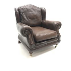 Thomas Lloyd wing back armchair upholstered in a brown leather, turned supports on castors