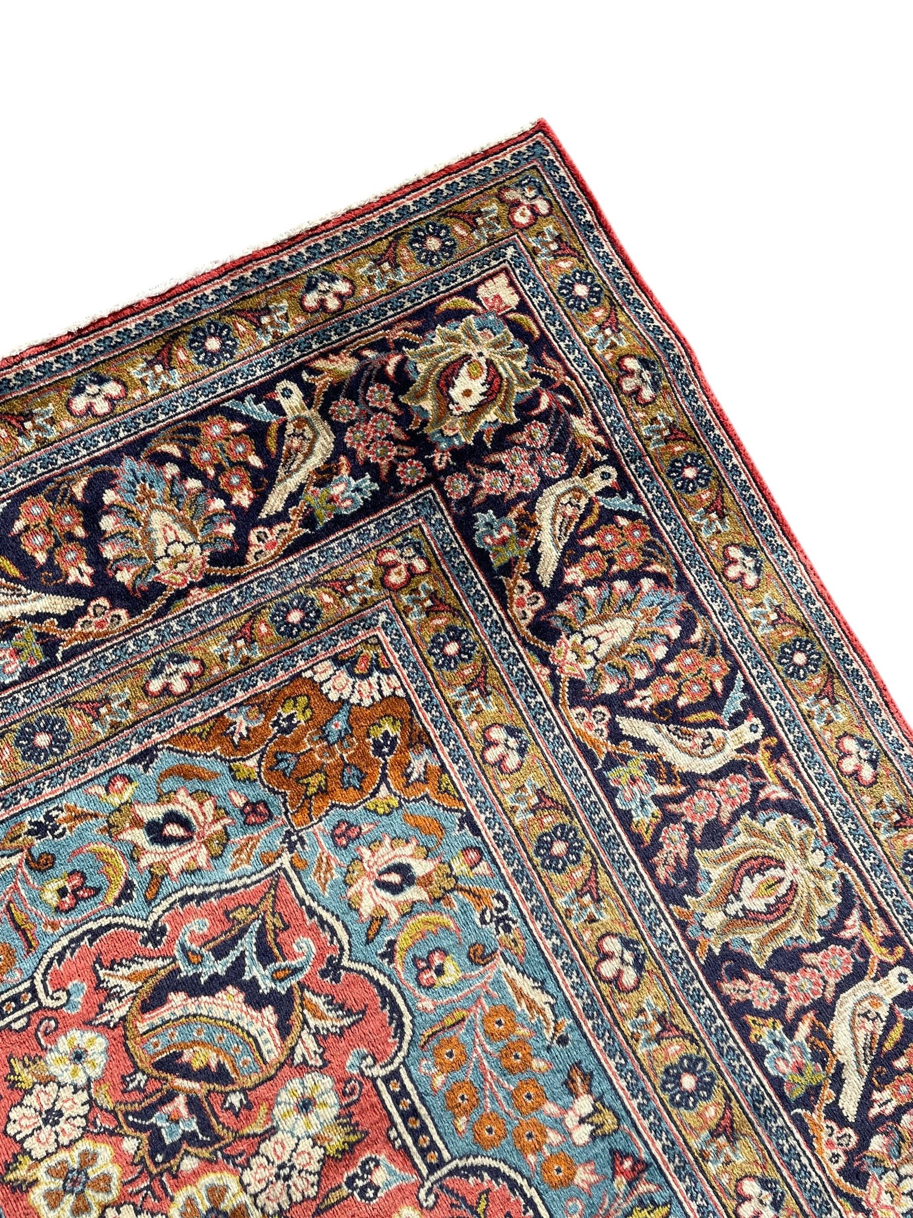 Persian Kashan peach ground rug, central rosette medallion surrounded by trailing branches and flower heads with bird motifs, light blue spandrels with further floral decoration, the main border with repeating palmettes and birds, within guard stripes