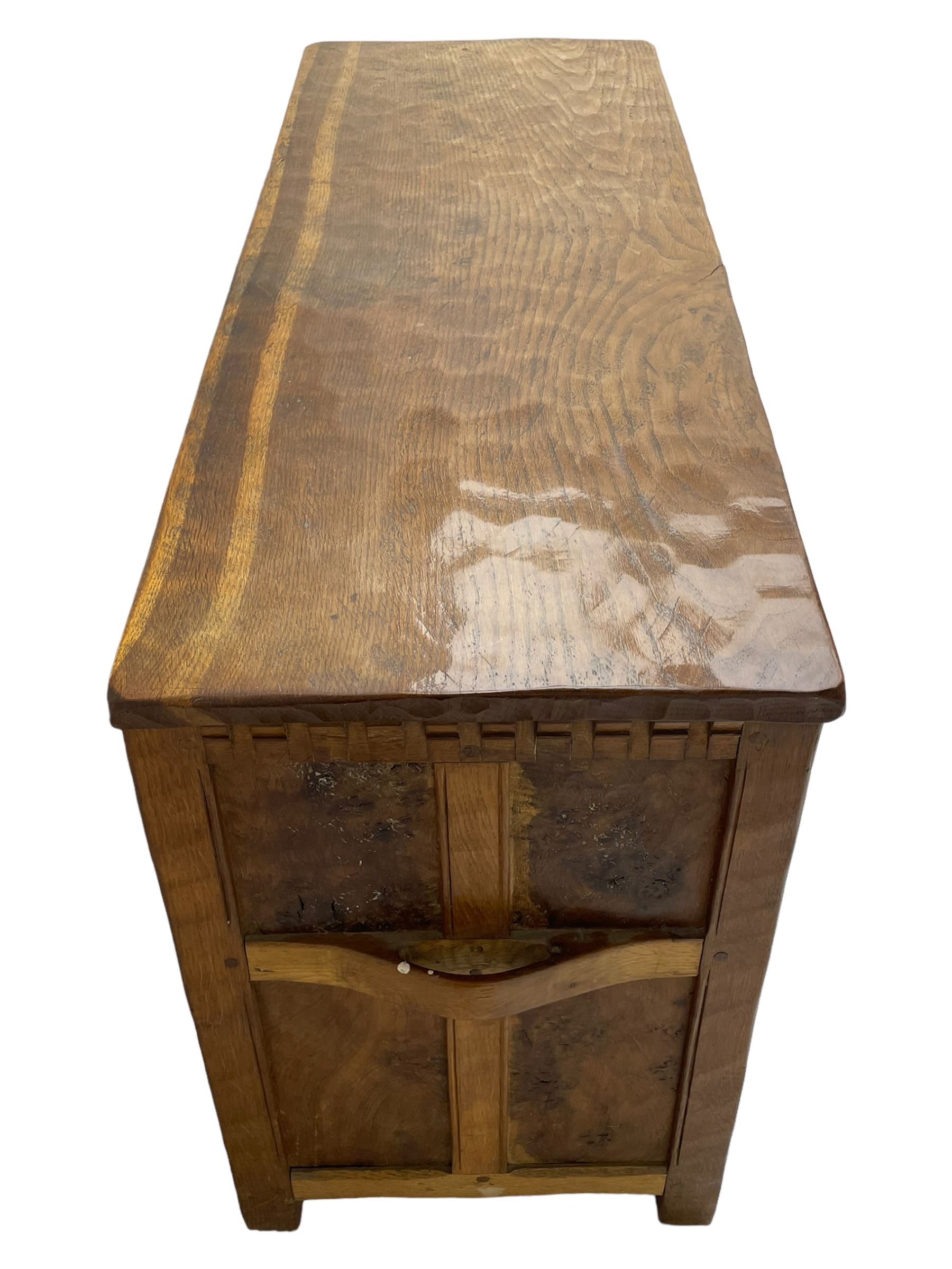 Gnomeman - oak blanket box, all-over adzing, the hinged top over figured and burr panelled front, decorated with carved crenellations and arcade, carved with gnome signature, pierced handles to each end forming the central rail, wrought metal hinges, on stile supports, by Tom Whittaker, Littlebeck, Whitby