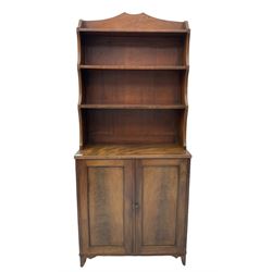 19th century mahogany bookcase on cupboard, raised three tier waterfall bookcase on cupboard enclosed by two panelled doors, on bracket feet