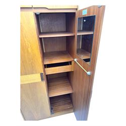 William Lawrence - mid-20th century teak double wardrobe, upper storage section over twin doors featuring recessed handles and contrasting horizontal panel, enclosing hanging rail compartment, towel rail, mirror, shelves and drawer, on plinth base with concealed castors