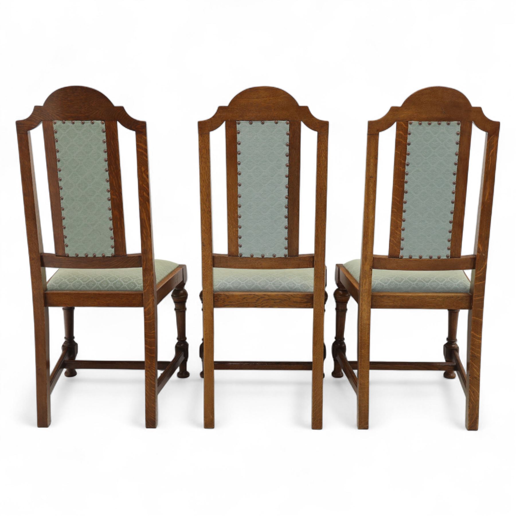 Victorian mahogany extending dining table, rectangular top with chamfered corners above a plain frieze raised on turned reeded legs with castors and two additional leaves, 197cm fully extended, and a set of six early 20th century oak upholstered chairs with drop-in seats, arched panelled back splat and close studded border on turned front legs joined by stretchers, 47x41x109cm 