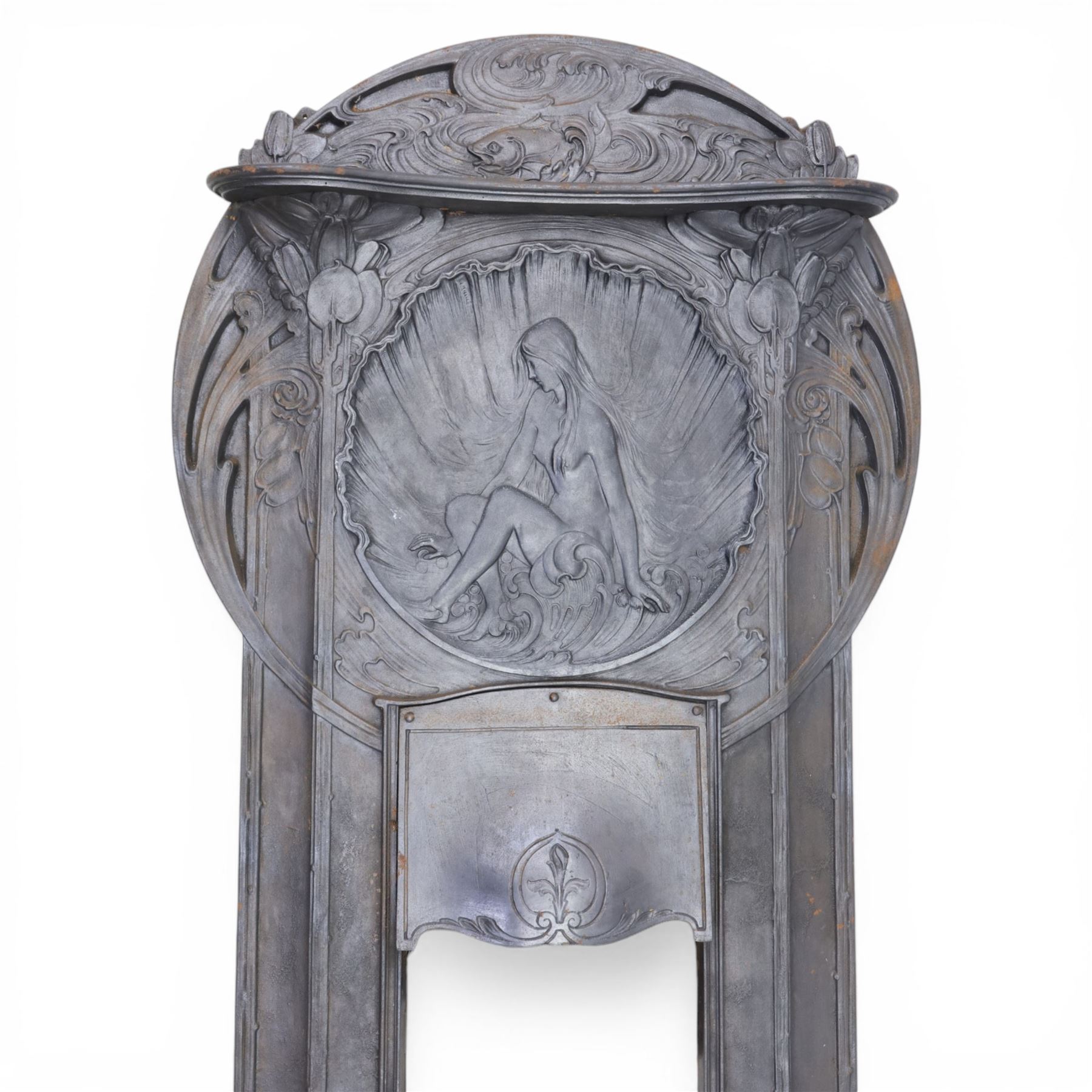 Art Nouveau cast iron fireplace, shaped hood with scrolling foliate crest, relief cast panel of female figure seated within shell form amidst wave motifs, uprights cast with foliate designs