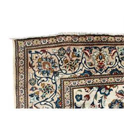 Persian Kashan ivory ground carpet, the field decorated with scrolling branches with foliate and palmette motifs, repeating border with stylised plant motifs, within floral and geometric pattern guard stripes 
