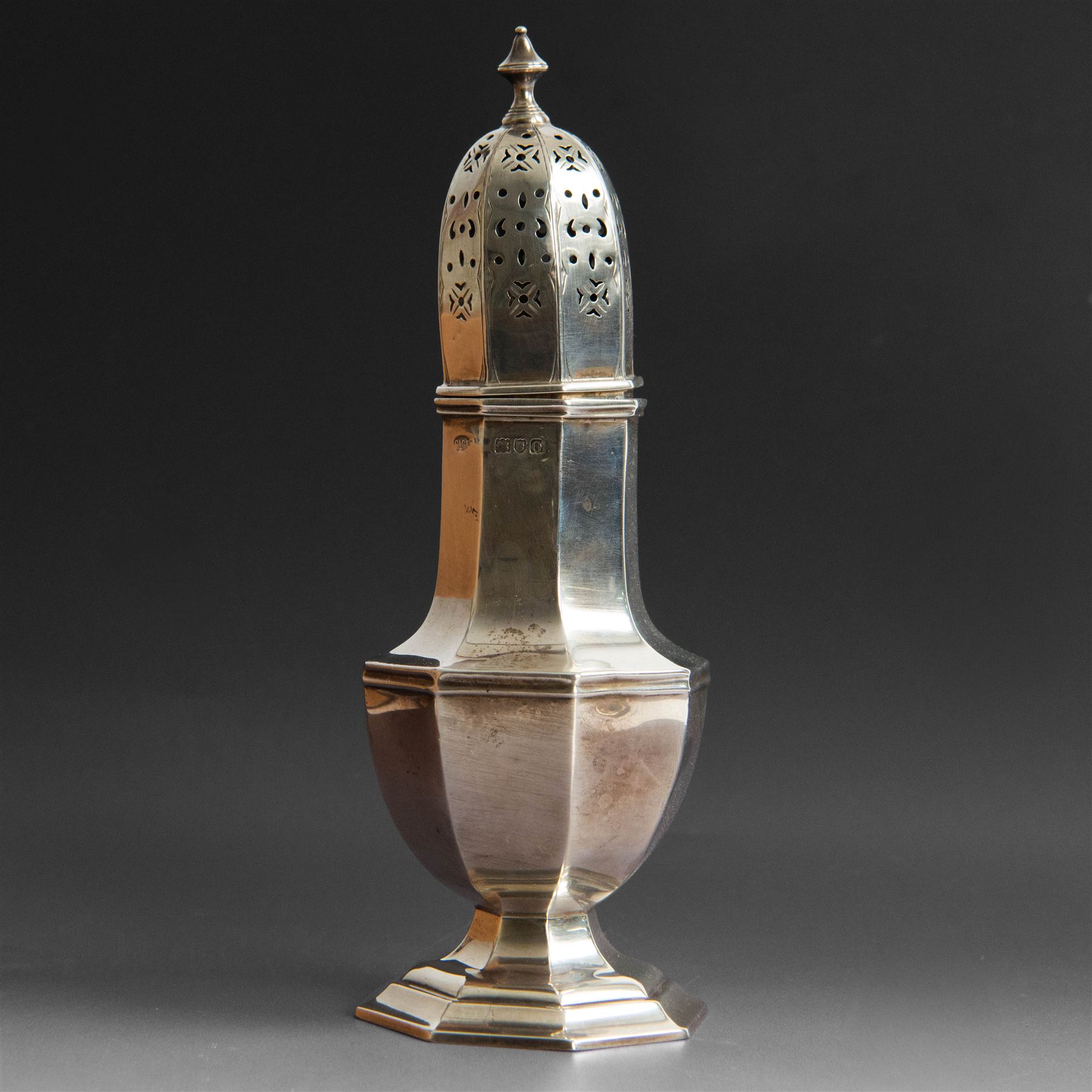 Edwardian silver sugar caster, of octagonal urn form, upon an octagonal foot, the removable pierced cover with urn finial, hallmarked Charles & George Asprey, London 1909, H21cm 