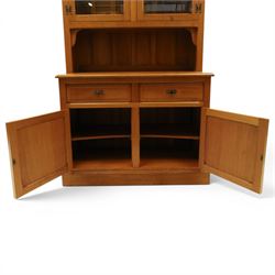 Knightman - oak dresser, the upper section fitted with twin glazed doors enclosing glass shelves, over open recess with panelled back, the base fitted with two drawers over twin panelled cupboards enclosing shelves, with recessed carved knight trademark, by Horace Knight of Old Mill Furniture, Balk near Thirsk
