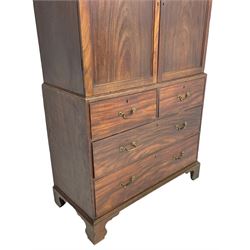 George III mahogany Gentleman's linen press, the projecting cornice over two panelled cupboard doors enclosing three sliding trays, the base fitted with two short over three long graduating cock-beaded drawers, lower moulded edge over bracket feet