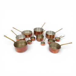 Twelve 20th century graduated copper pans with brass handles, some stamped Made in France,...