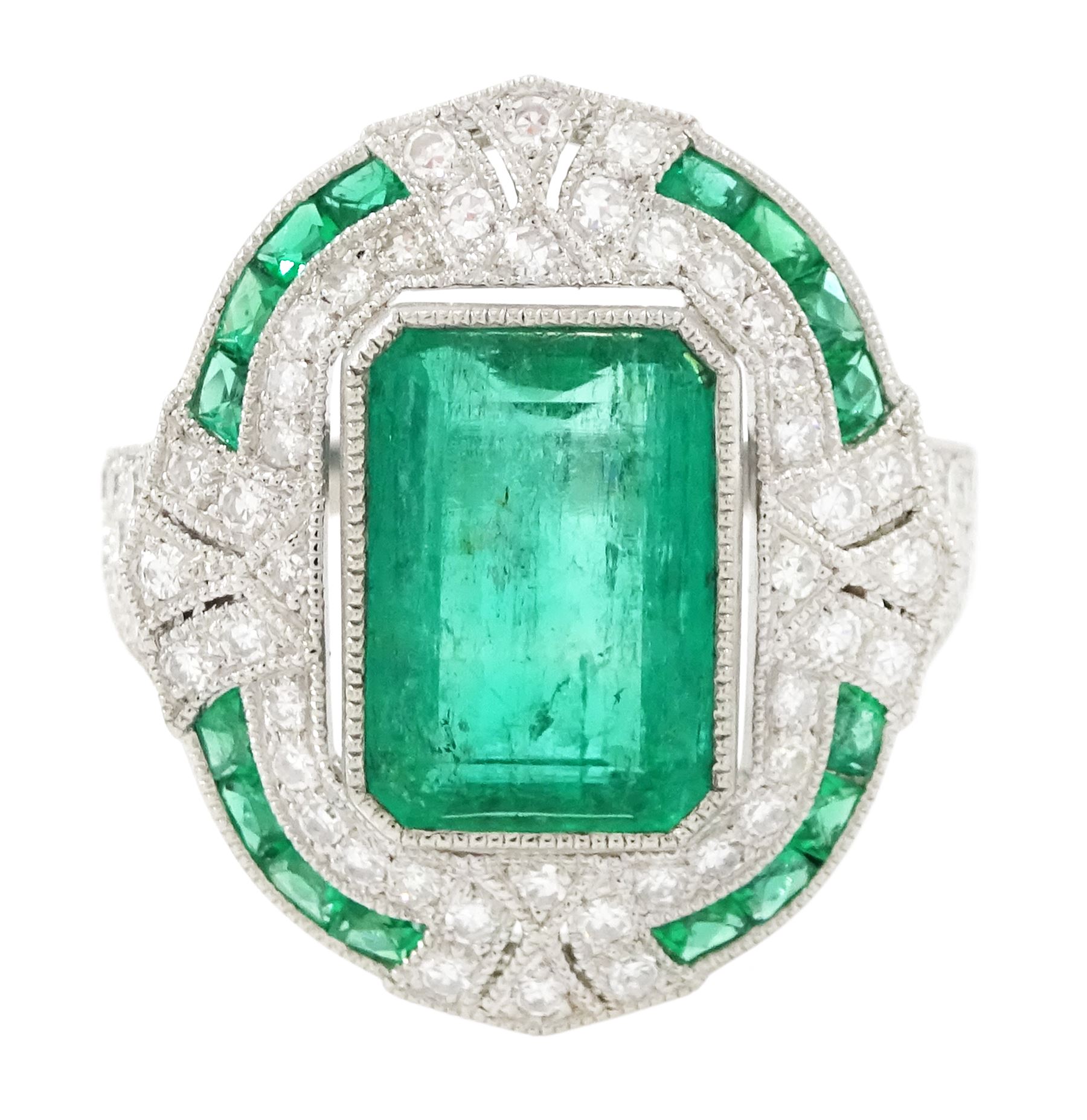 Platinum emerald and diamond milgrain set dress ring, single octagonal cut emerald of 2.40 carat, surrounded by single cut diamonds and a border of calibre cut emeralds, with fancy pierced design gallery diamond and engraved flower head shoulders, stamped 850 Plat