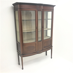  Edwardian inlaid mahogany shaped front display cabinet, projecting cornice, two glazed doors enclosing lined interior with two shelves, square tapering supports on spade feet, W122cm, H179cm, D46cm  