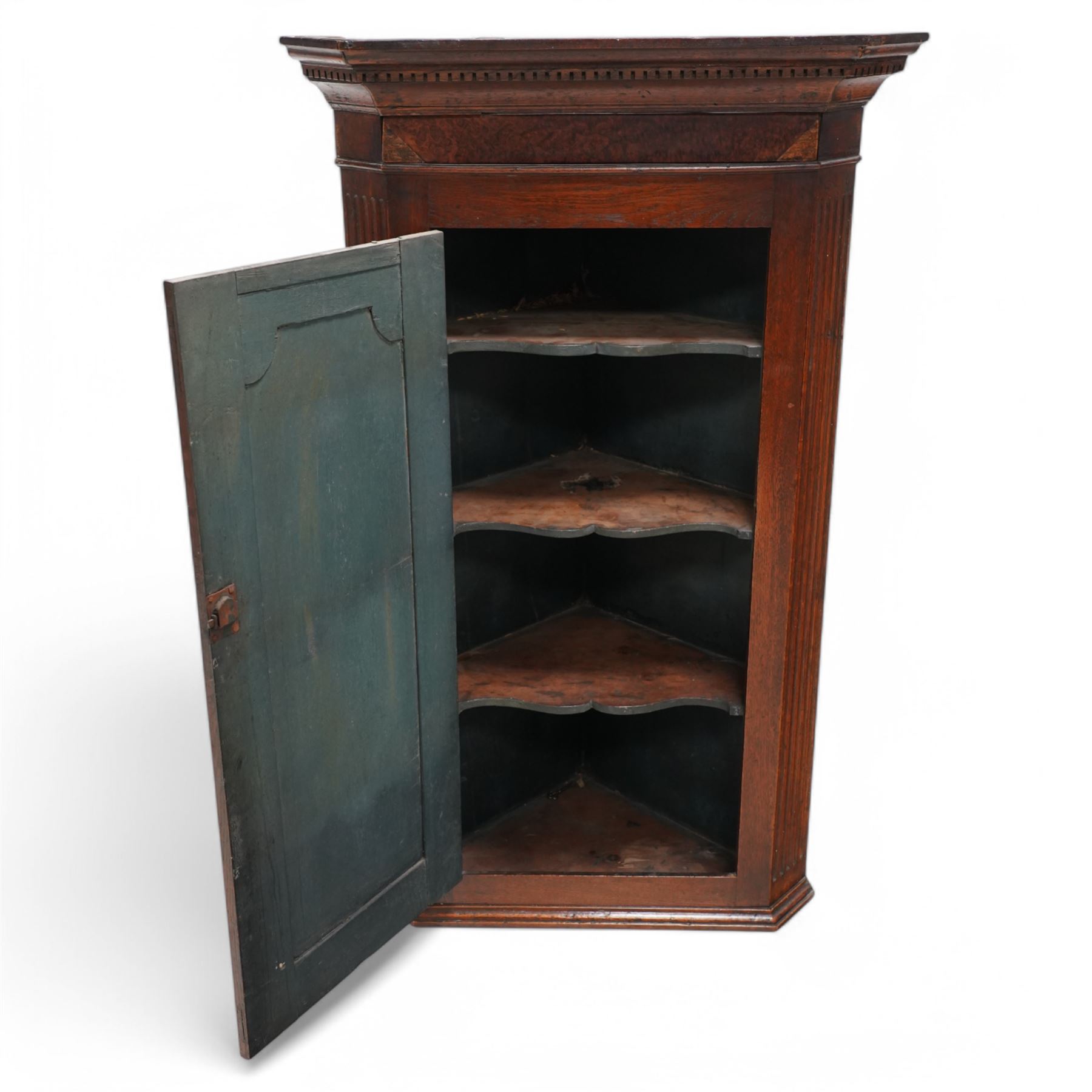 19th century mahogany corner wall cupboard, with projecting cornice and dentil moulding above a single door with shaped fielded panel and satinwood fan inlay, flanked by fluted pilasters, fitted with shaped interior shelving