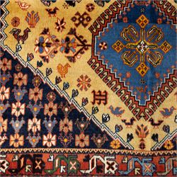 South Persian Yallameh hand-knotted rug, ivory ground, with a central stepped pole medallion design in blue and terracotta tones, surrounded by geometric tribal motifs incorporating stylised flowerheads, birds, hooked devices and angular vine work, enclosed by dark navy spandrels and a terracotta border with repeating geometric motifs, flanked by narrow patterned guard stripes, with cotton fringes