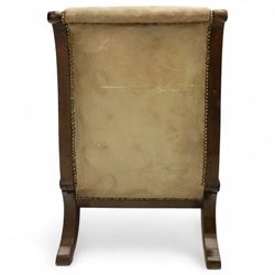 William IV mahogany gentleman's library reclining armchair, leather button upholstered and brass-studded back and seat, above leather-covered arms terminating with carved roundels and foliate scroll-carved ends, underside with brass mechanical trigger reclining lever, the apron with retractable foot rest, supported on lappet carved and turned legs with brass castors, circa 1835