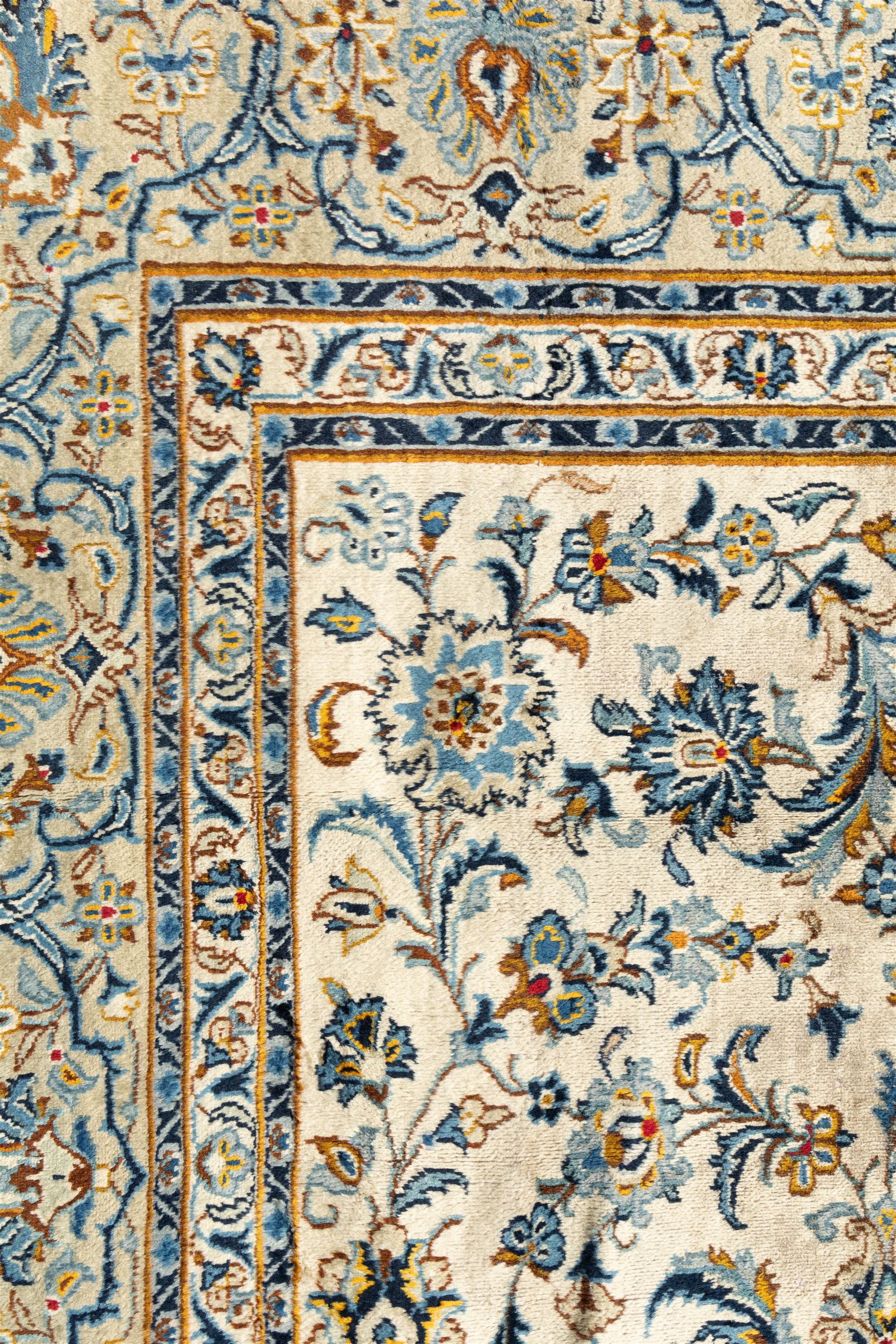 Central Persian Kashan hand-knotted carpet, ivory field profusely decorated with an all-over scrolling vine, palmette, and lotus design in shades of soft blue, pale gold, and green within floral borders