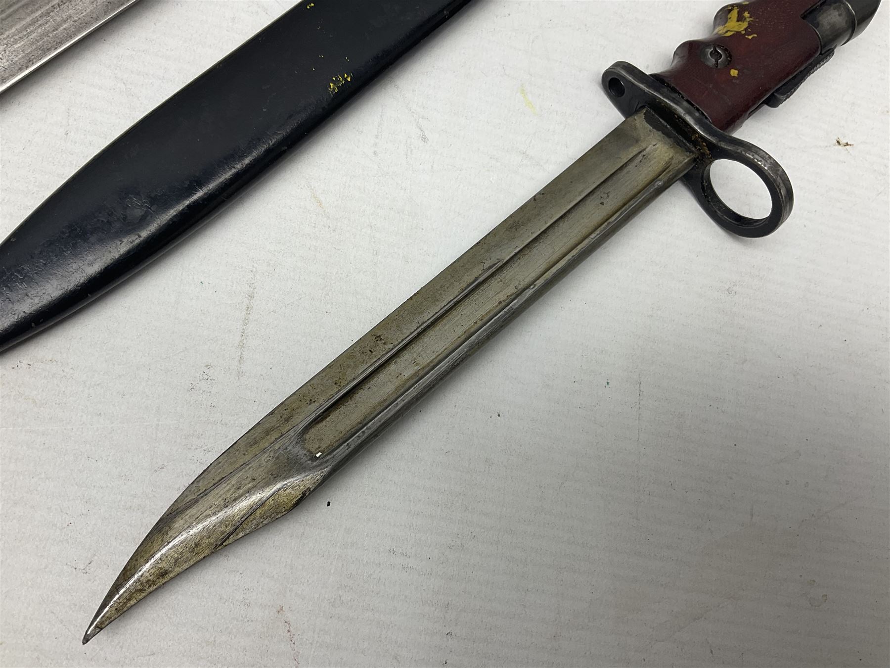 British No 7 MKI knife bayonet with 20cm single edged fullered clipped point blade;  blackened steel, large muzzle ring cross-guard; blackened swivelling pommel marked 'F5H'; red Tufnol composite grips; in blackened steel scabbard L33cm overall; British Pattern 1888 bayonet with scabbard; and German Ersatz bayonet with scabbard (3)