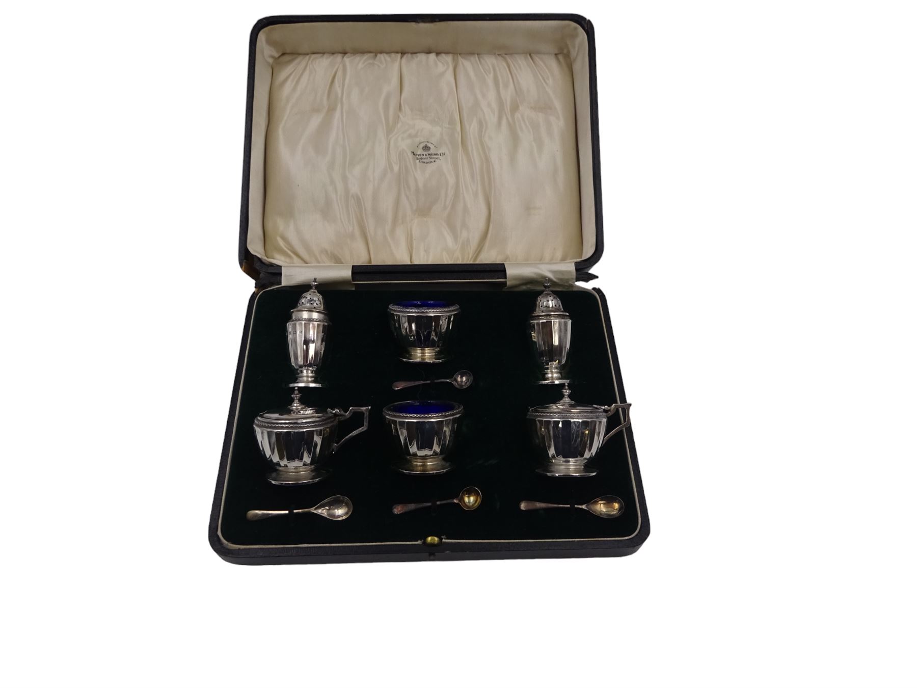 1920s silver six piece cruet set, comprising two mustard pots with covers, two open salts and two pepper pots, all of circular faceted form, mustards and salts with blue glass liners, hallmarked Mappin & Webb, Birmingham 1928, with four matched silver condiment spoons, hallmarked, contained within fitted case 