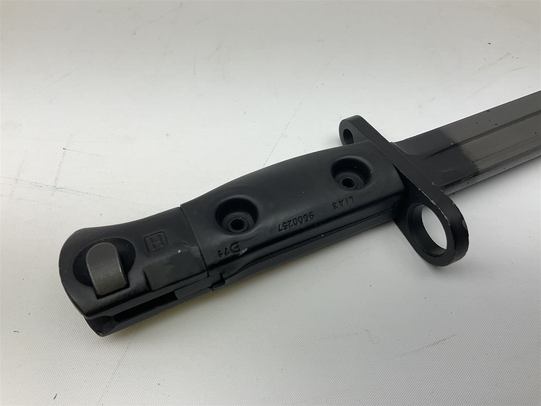 British Army L1A3 SLR Self Loading Rifle bayonet, with 20.5cm Bowie type fullered blade, hooked pommel with working push release button, grip secured by two deeply recessed rivets and marked L1A3 9600257 D71; in matching black scabbard L32.5cm overall