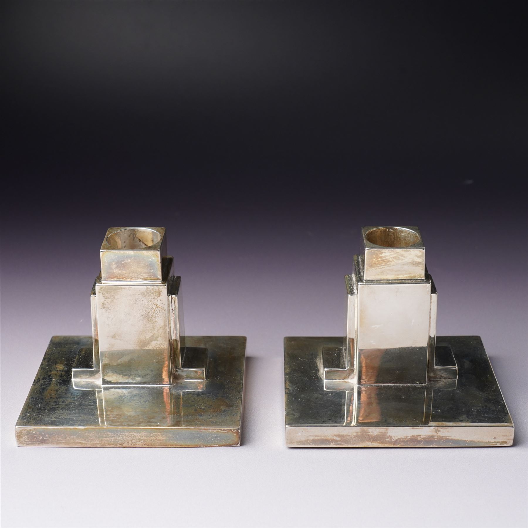 Pair of Art Deco silver candlesticks with square section stems supported by two lappets on a rectangular base H7.5cm x W9.5cm Sheffield 1935 Maker Walker & Hall