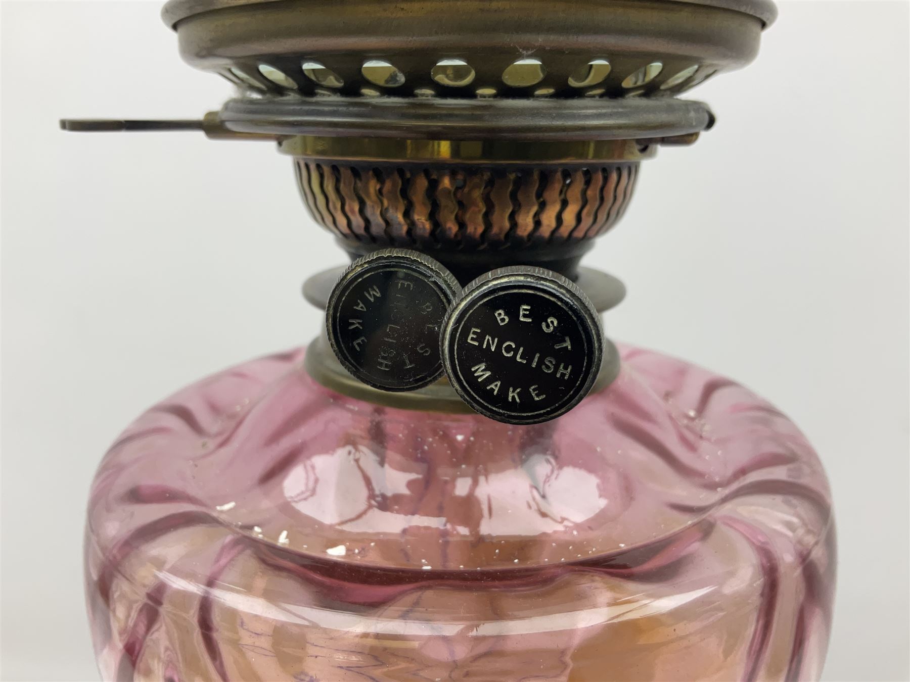 Victorian table oil lamp with black glazed stepped circular base, reeded brass column, moulded pink glass reservoir, duplex burner and frilled rim frosted glass shade with clear glass chimney H69cm