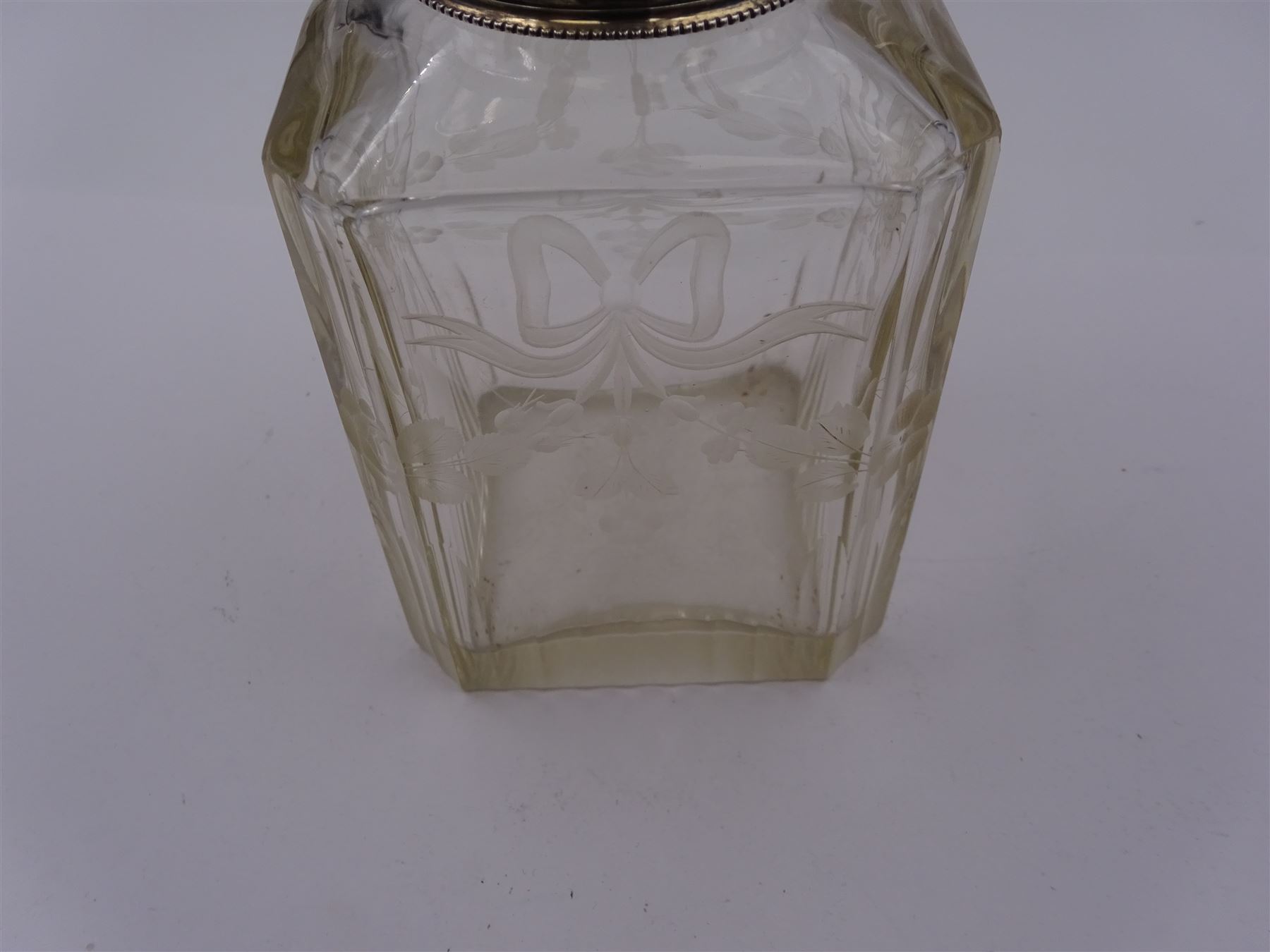 Early 20th century French silver mounted glass scent bottle, the faceted rectangular glass body etched with swags of flowers united by ribbons, with cylindrical silver cover embossed with foliate detail and beaded decoration with gilt interior, marked with Minerva's head, with white metal collar and glass stopper, H17cm