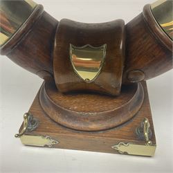 Early 20th century oak and horn dinner bell, the silvered bell suspended from a pair of cow horns, with silver plated mounts and blank shield shaped cartouche, upon square base, H37cm