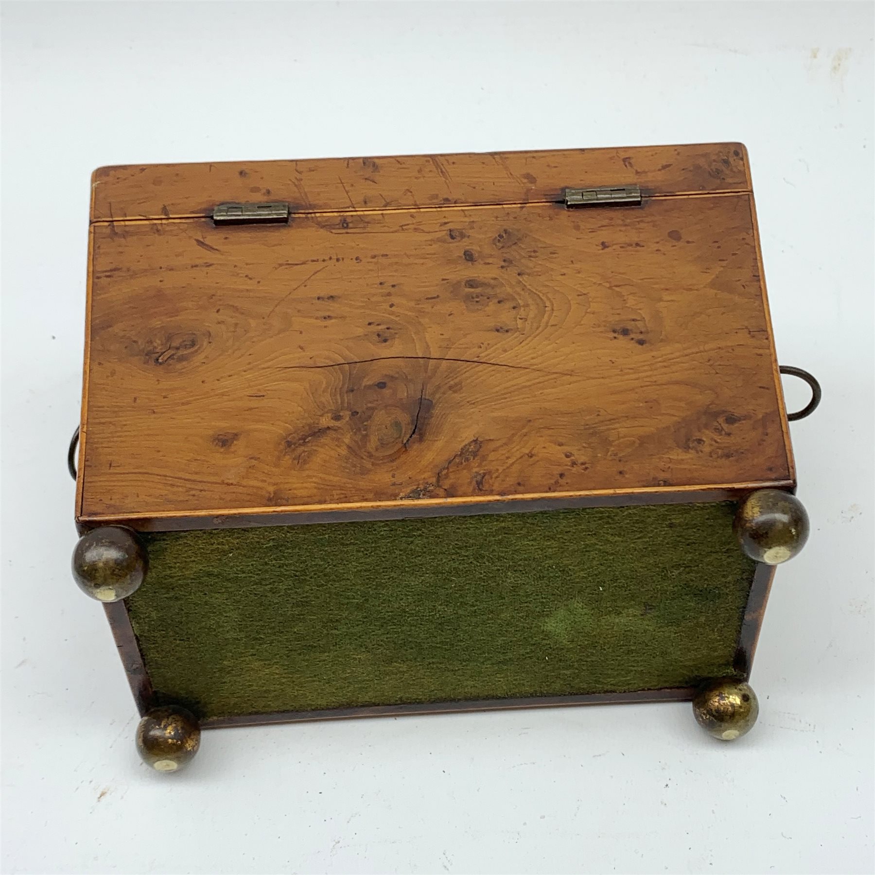 George III burr yew tea caddy, of sarcophagus form with lion mask ring handles and four brass ball feet, the hinged lid opening to reveal two compartments with cross-banded lids and traces of metallic paper lining, L19cm