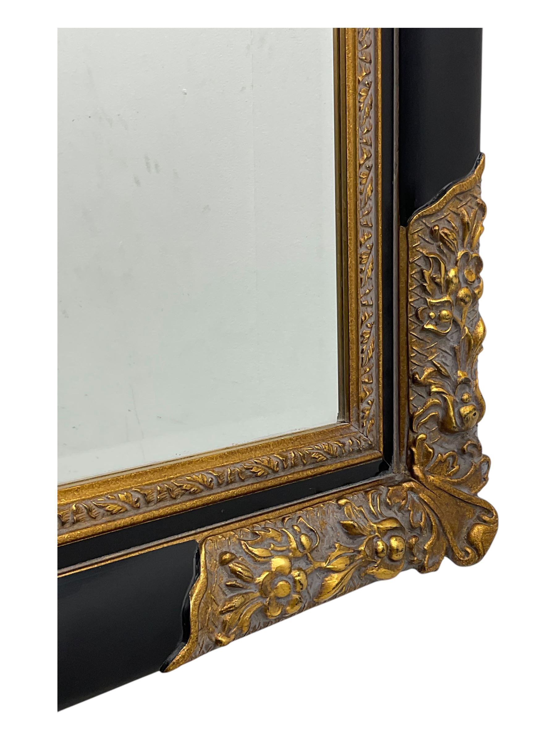 Early 20th century wall-hanging mirror, rectangular bevelled mirror plate within ebonised frame, gilt mounts to the corners carved with floral motifs 