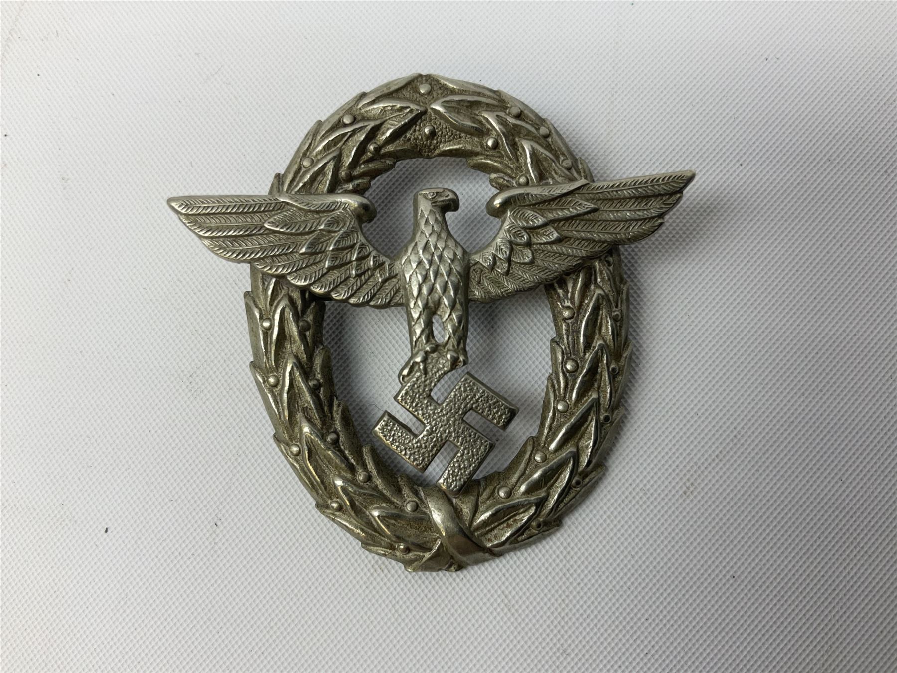 Three WW2 German visor cap badges comprising Police eagle, Political leaders eagle and Norwegian Quisling Party; all with fixings; and WW2 Polish visor cap badge (4)