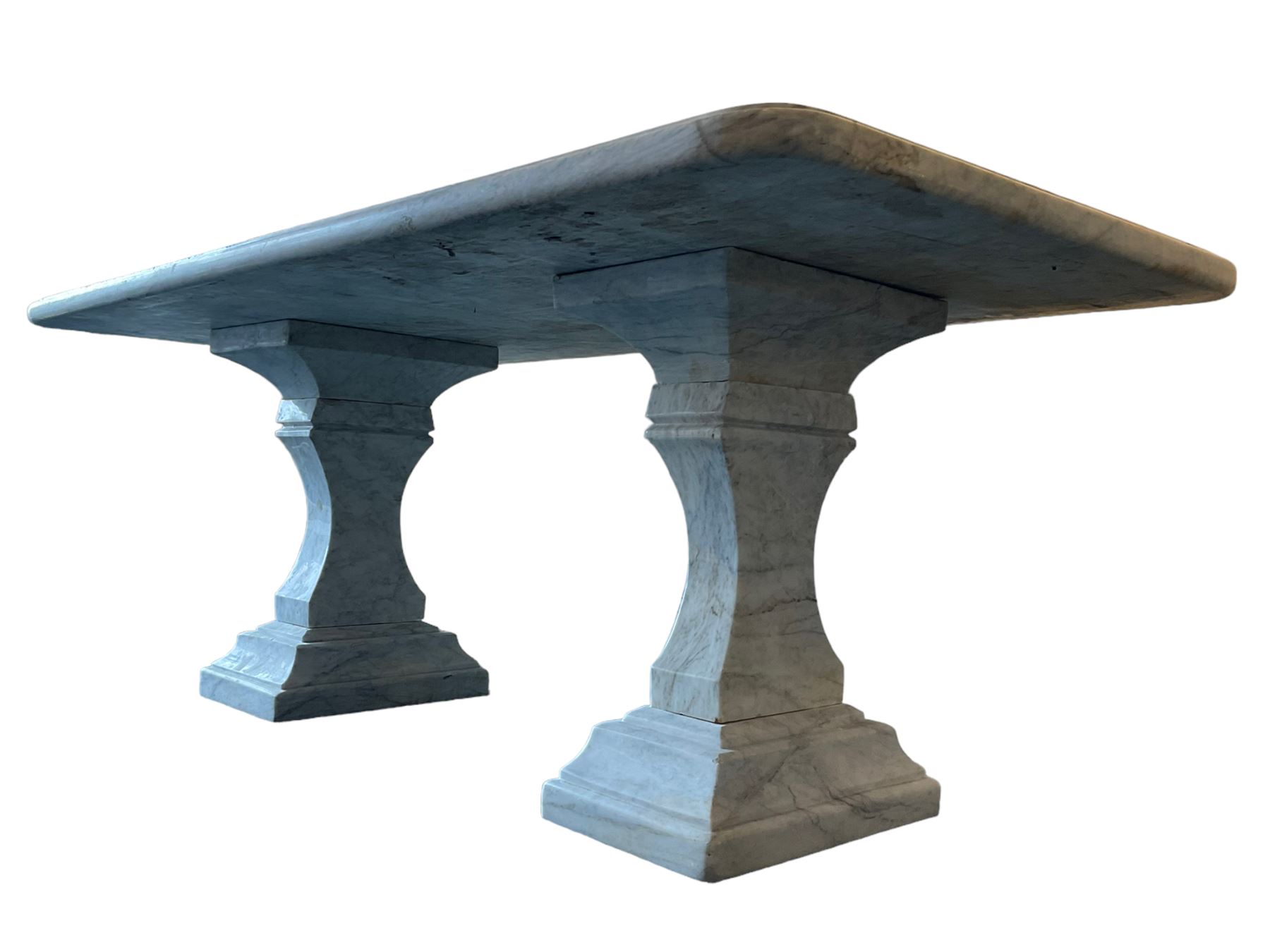 Classical Grecian design Carrera marble centre table, the rectangular single slab top with rounded corners and carved edge, raised on twin pedestals comprised of three pieces with a waisted column on a stepped plinth