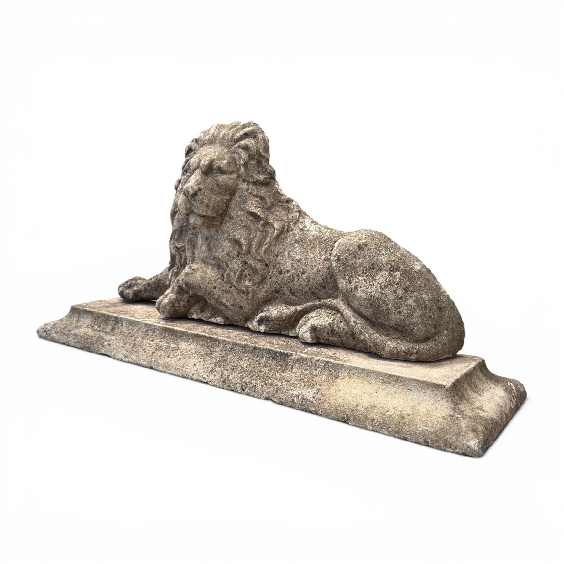 Neoclassical design cast stone garden lion, modelled recumbent with raised and flowing mane, on rectangular plinth base, with flat plain reverse, in weathered finish