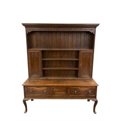 19th century oak dresser, projecting cornice over foliate carved frieze, the three-tier plate rack fitted with panelled cupboards to either side, base with central cupboard flanked by two drawers, raised on cabriole supports carved with acanthus leaves