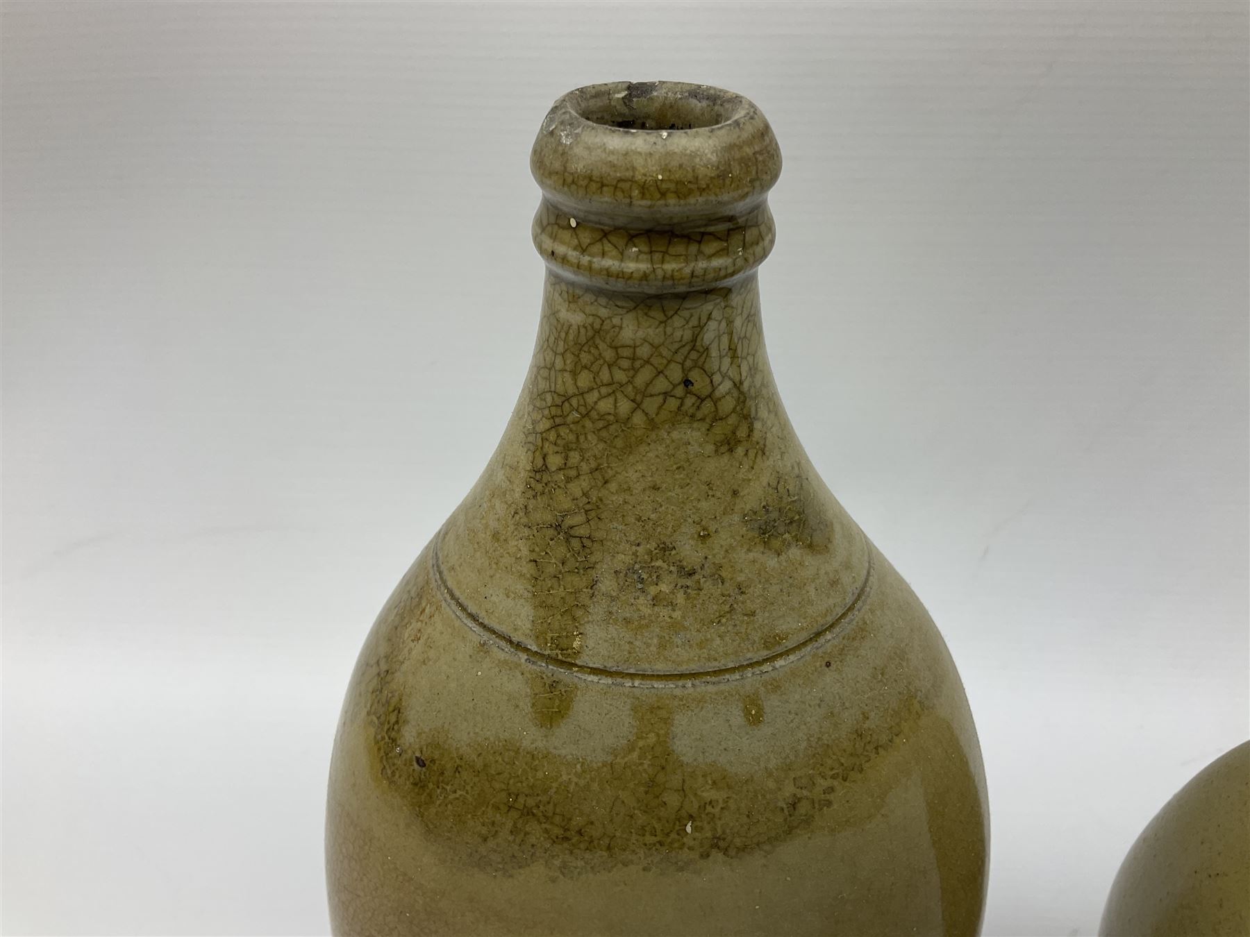  19th century salt glazed stoneware gin bottle impressed John Shaw, Red Lion Vaults, Whitefriargate, Hull of bulbous oval form H27cm and another with impressed label for J. Christie Mytongate Hull (2)  