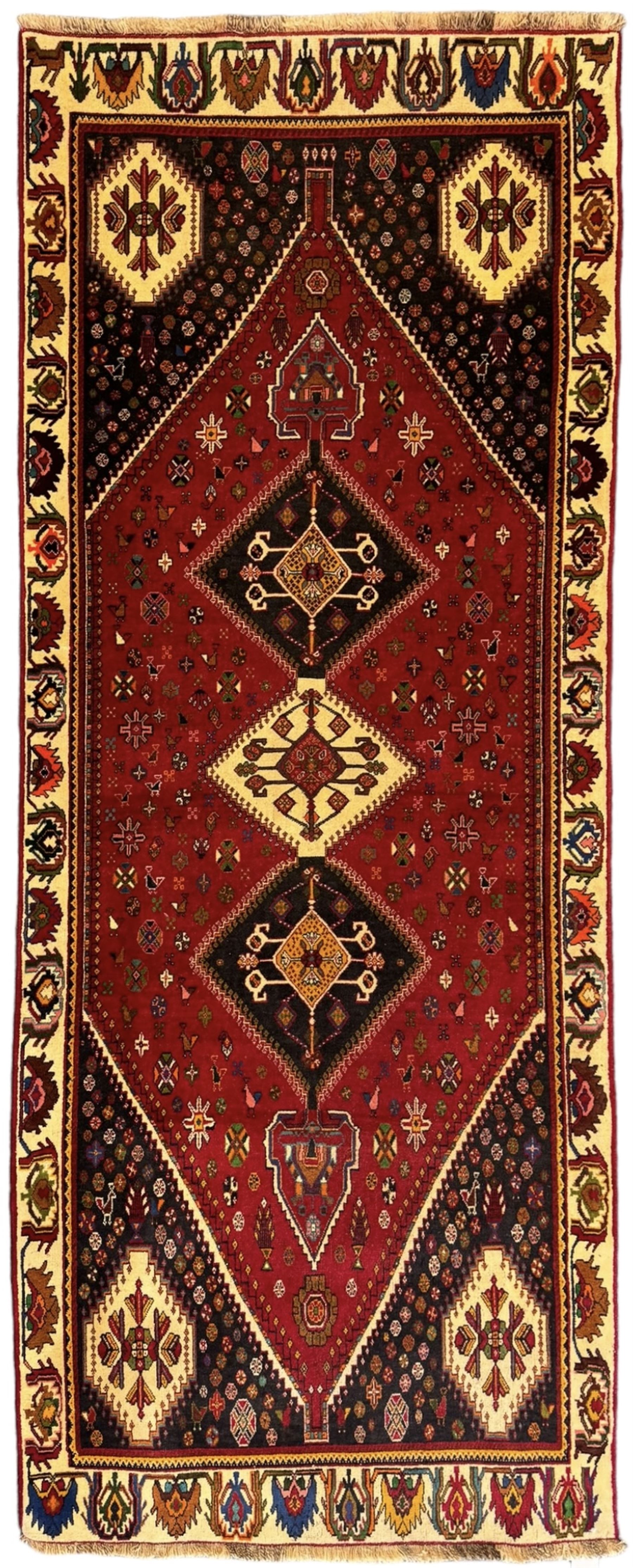 South West Persian Qashqai red ground runner, the crimson field decorated with three connected lozenges, surrounded by small stylised motifs of bird and plants, indigo spandrels with further stylised motifs, the border with repeating floral design 