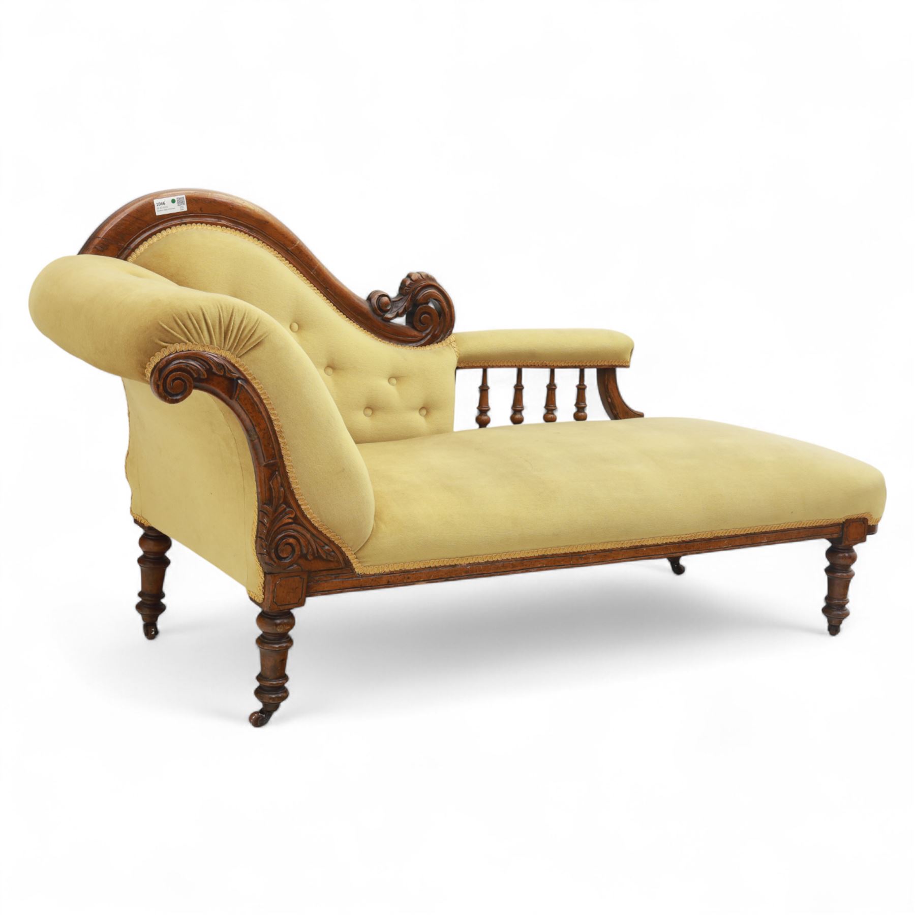 Victorian walnut chaise longue, carved with scrolling acanthus to the end supports and seat rail, upholstered in mustard coloured velvet, shaped and buttoned back and side with turned spindle gallery, raised on short turned legs with ceramic castors 
