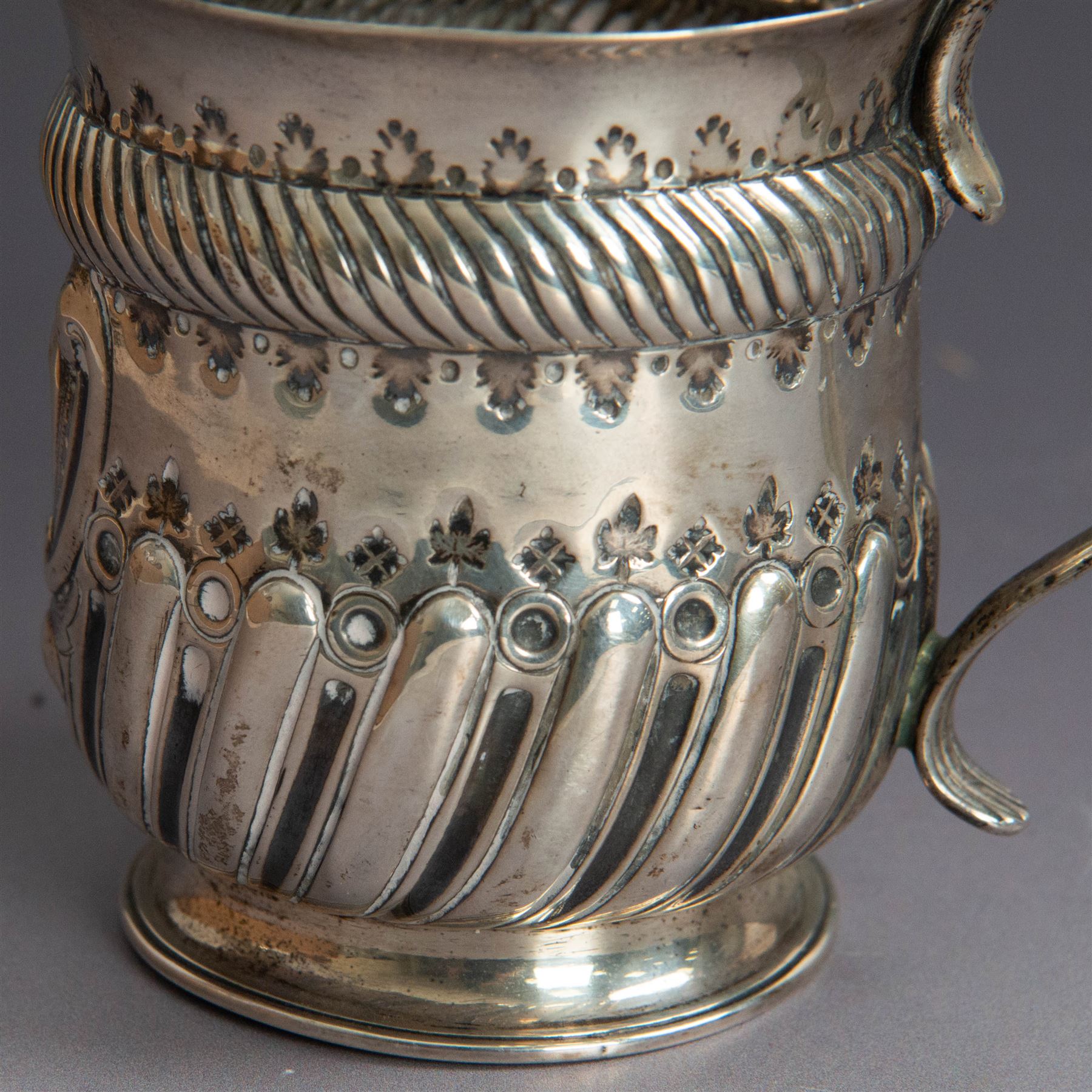 Victorian silver christening mug, of circular form with C scroll handle, embossed with scrolls and foliate decoration, with vacant oval cartouche to body, hallmarked John Aldwinckle & Thomas Slater, London 1890, contained within a tooled leather fitted case, mug H8cm